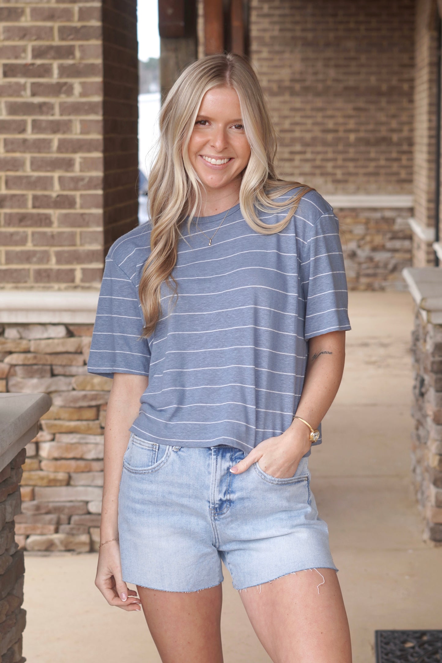 Woman wearing blue and white striped crop t-shirt paired with blue jean shorts