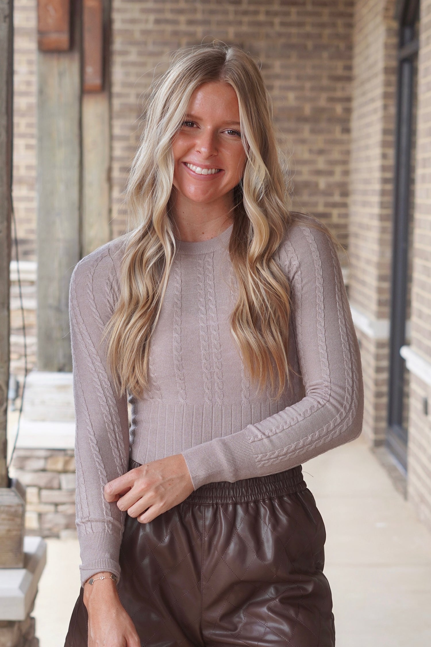 Woman wearing stone colored fitted  ribbed bodysuit paired with brown shorts