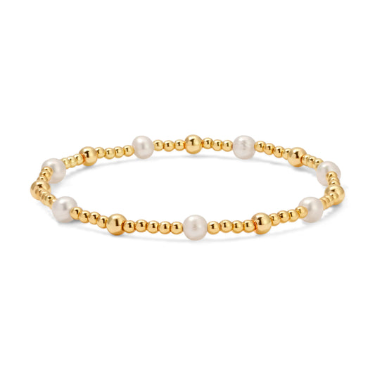 Gold bracelet with white pearls on a white background
