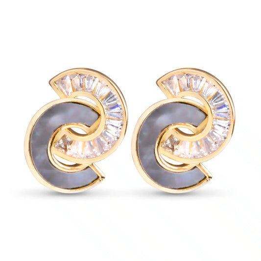 A pair of elegant gold earring featuring a swirling design with a gray center and sparking clear stone. 