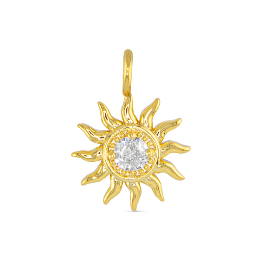 Gold necklace charm in the shape of a sun with a faux crystal in the center