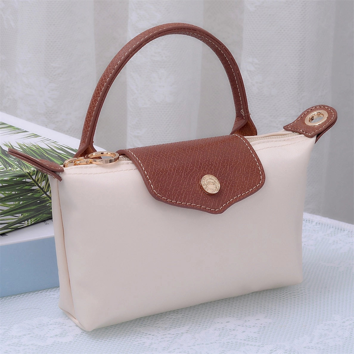 Small cream colored handbag with brown leather and gold accents 