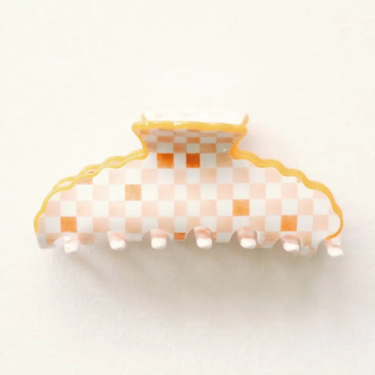 A claw hair clip featuring a white and light orange checkered pattern with a wavy yellow-orange border