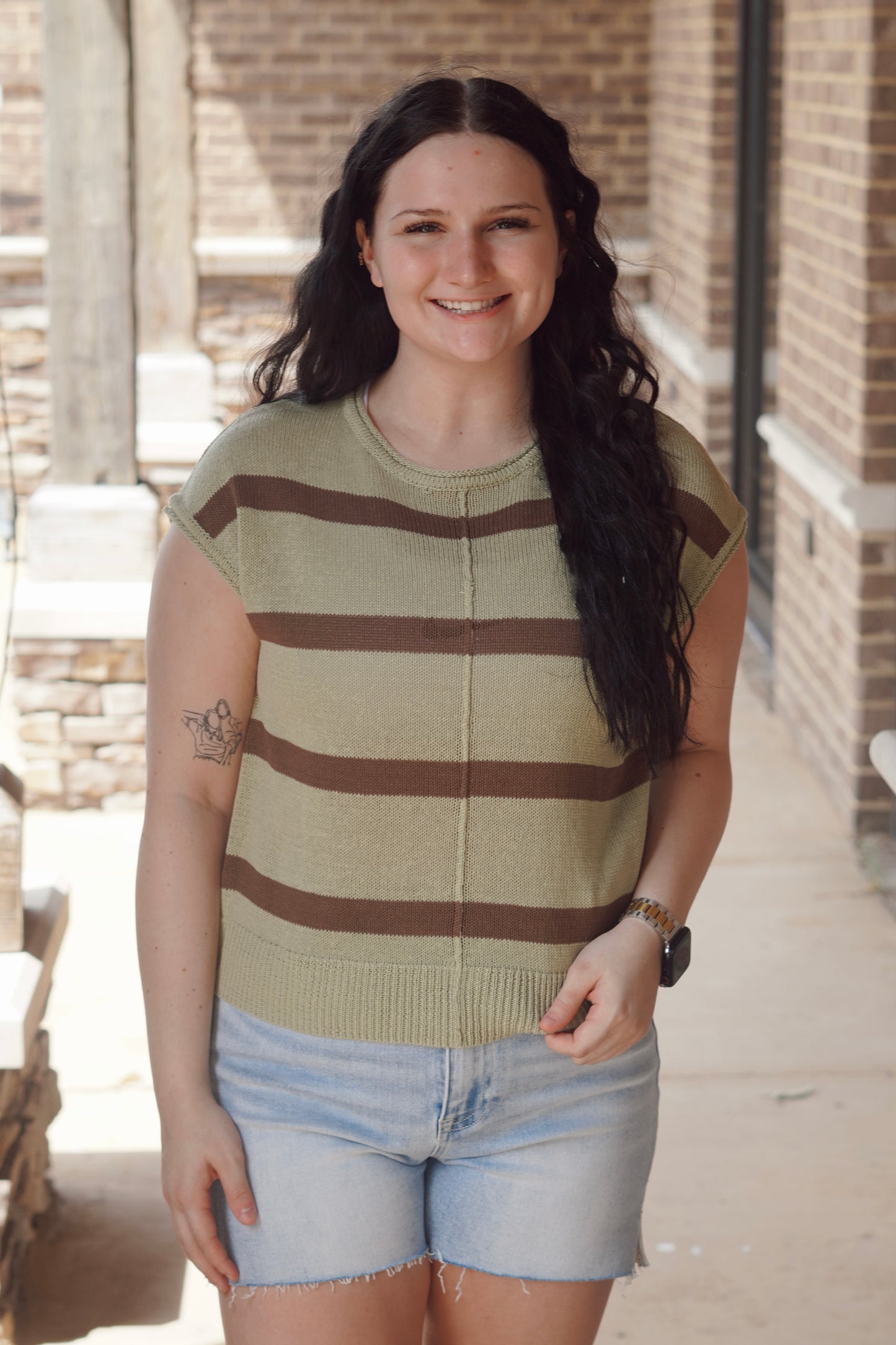 Women wearing green and brown striped top with, short sleeve, round neckline, knit material.