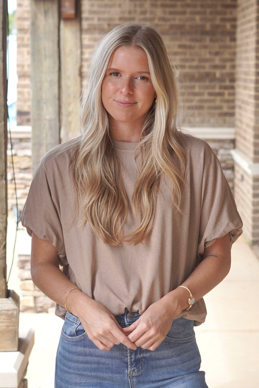 Women wearing a bubble sleeve taupe top, round neckline, and elastic band at the bottom 