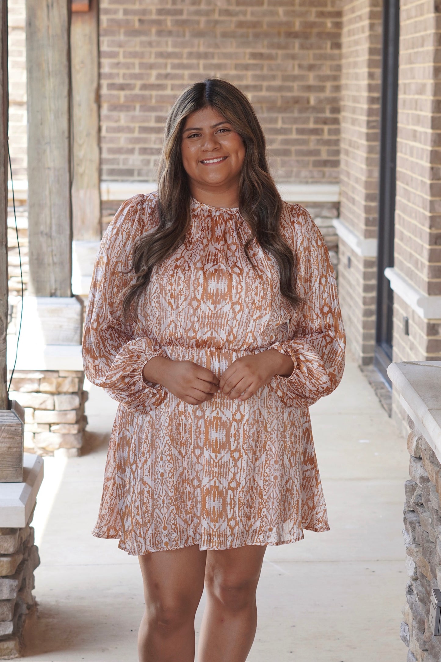 Woman wearing a white and gold geometric print mini dress with a cinched waist 