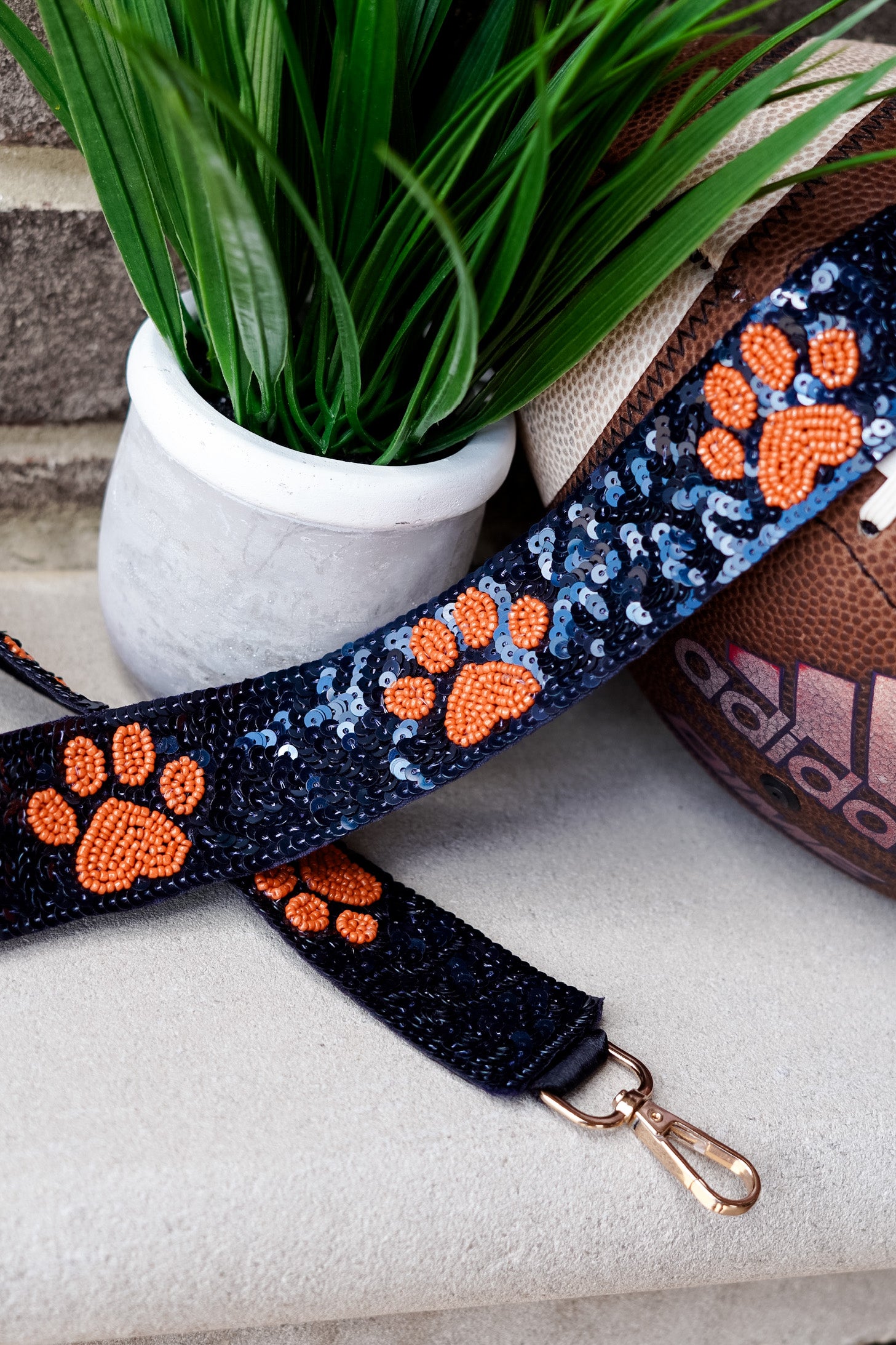 Clear bags can be such a bore when your outfit is on point for game day!! No fear, grab a Game Day Beaded Crossbody Strap whether you are Rolling with the Tide or headed to the Plains!!  Sequin Game Day Strap 46.5" including gold hooks. Navy beaded strap with orange paw prints.