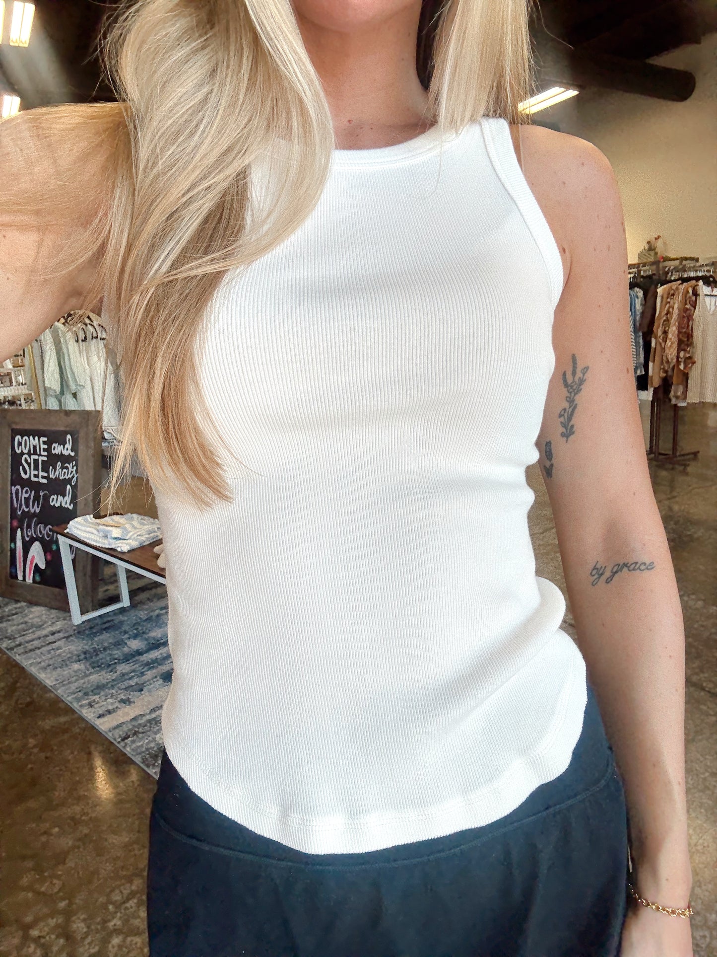 Women wearing a ribbed white tank, fitted style and a round neckline.  
