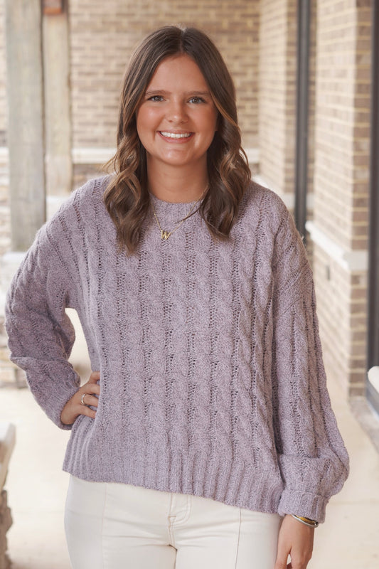 Woman wearing a light purple knit sweater paired with cream jeans
