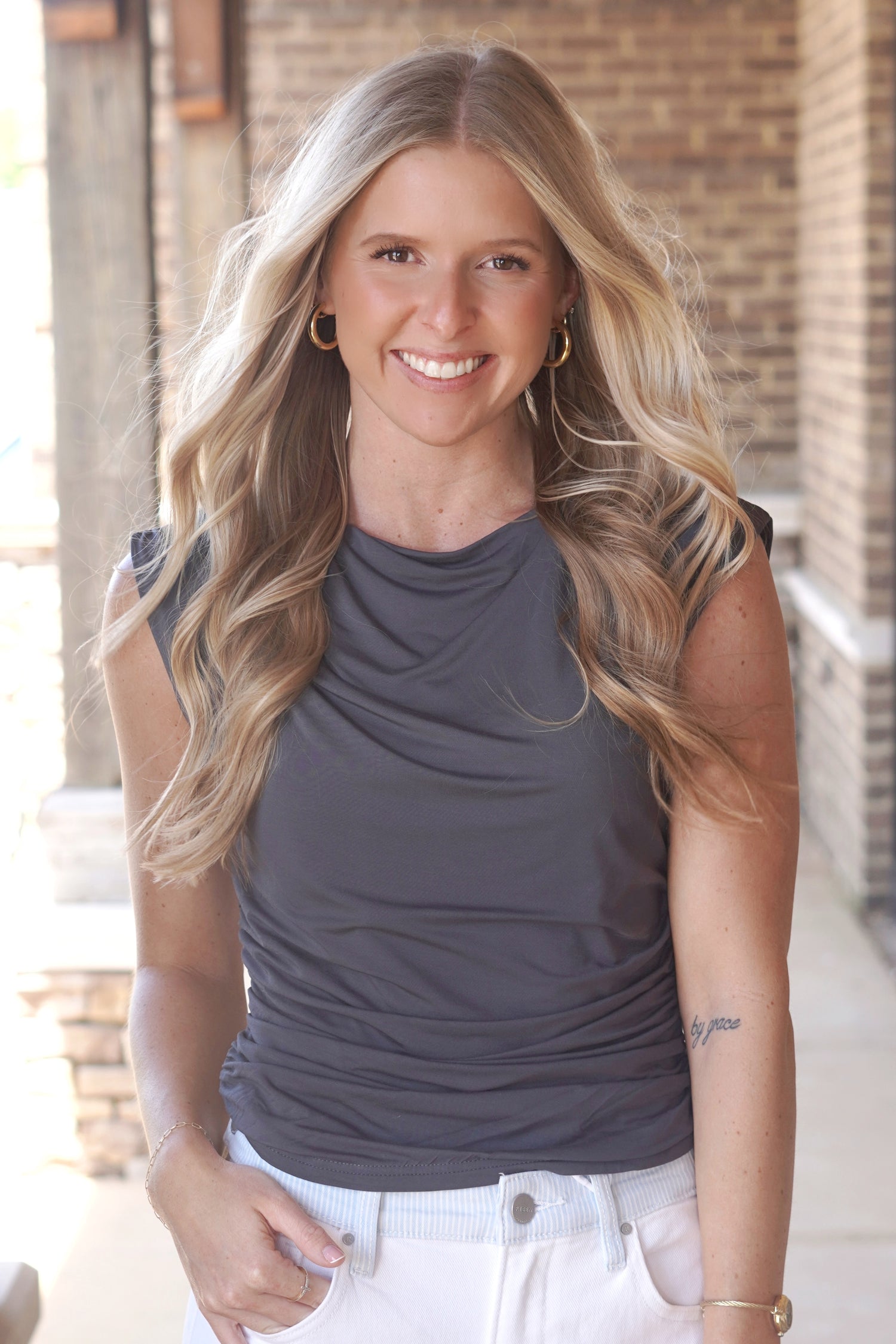 Women wearing a grey top with a 
Round Neckline and a Cinched Waist, cap short sleeve. 