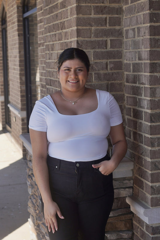 A women wearing a short-sleeved white bodysuit with a square neckline, Tight Fitted. 