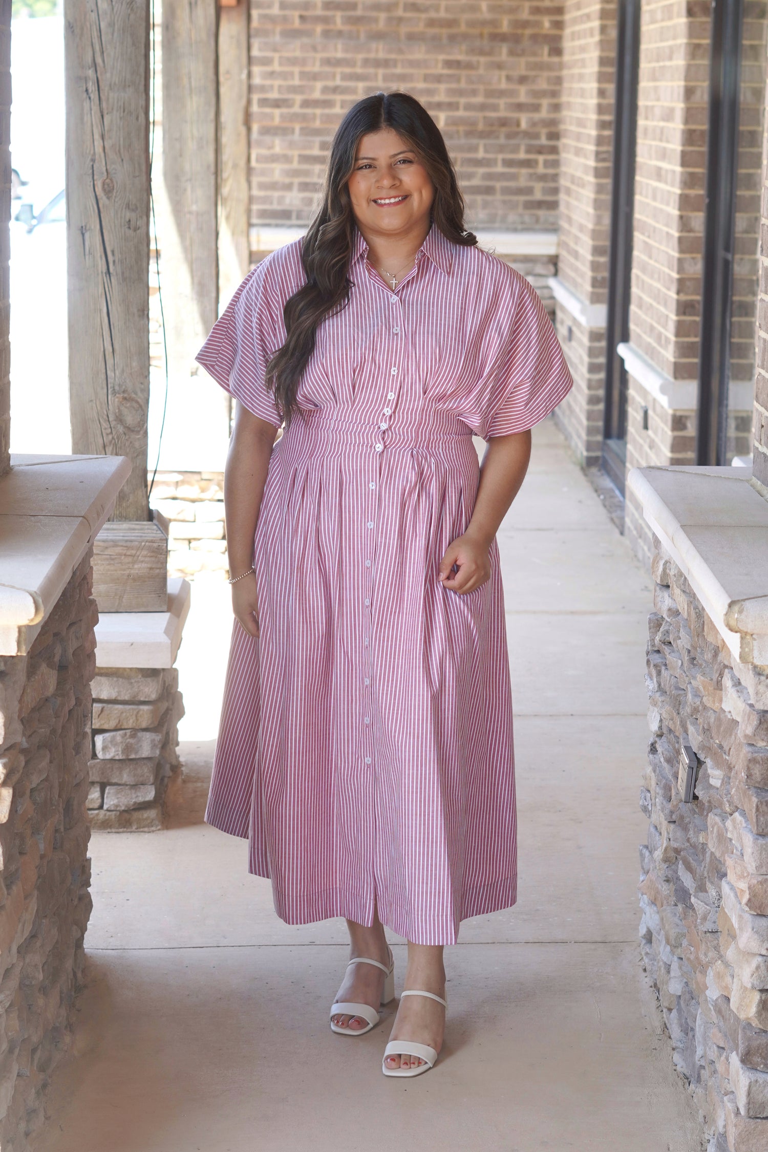 Women wearing a maxi red striped dress, buttons going down the middle,  collar neckline, short sleeve.