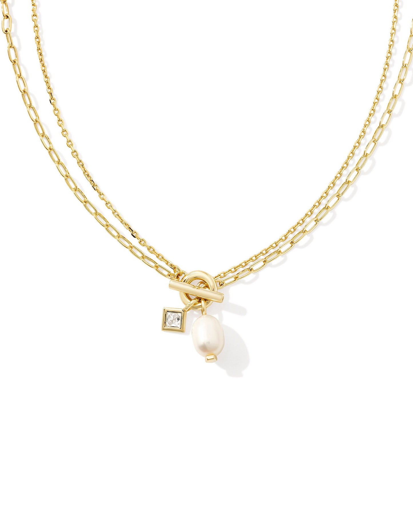 two strand gold necklace joined together with a toggle clasp and a crystal charm and a pearl charm