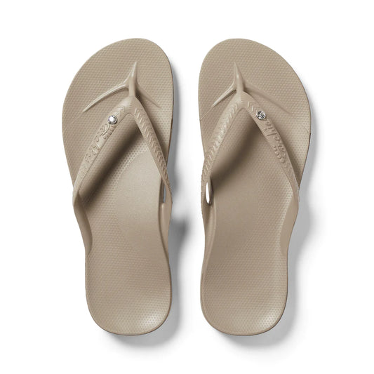 A pair of taupe arch support flip flops with a crystal detail on foot strap.