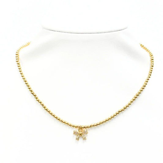 Gold beaded necklace with crystal bow charm