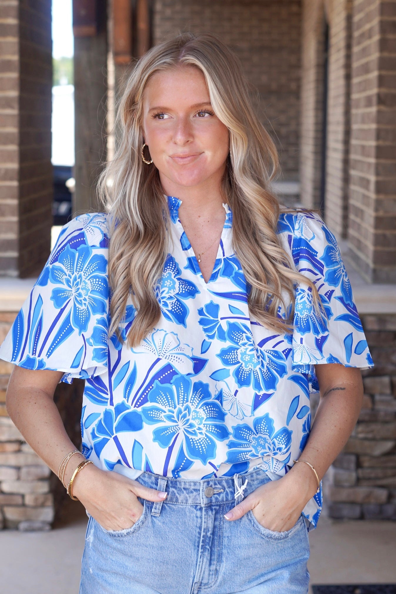 Women wearing a White short sleeve top with royal blue and light blue summer floral print. V-neckline. Full length top.