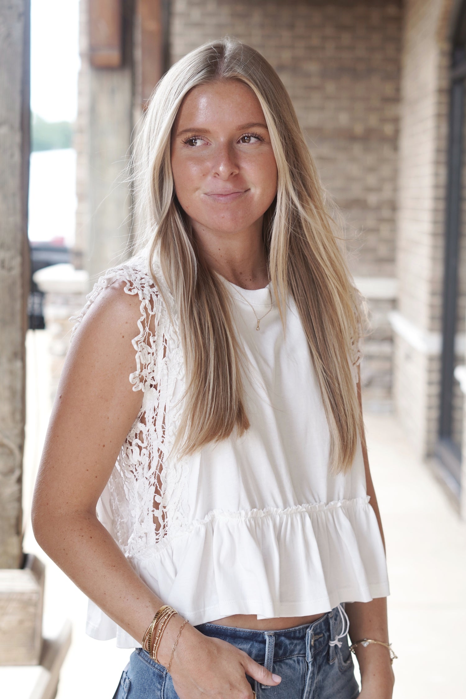 White sleeveless top. Ruffled bottom hem. From shoulder to beneath the armpit, lace trim, completely see-through. Semi-cropped. 