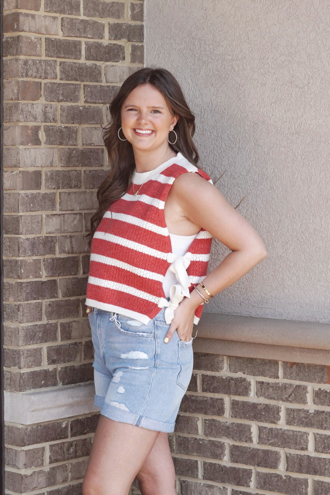 Red and white striped sweater like top. Sides of the top tie. Round neckline. Sleeveless. 