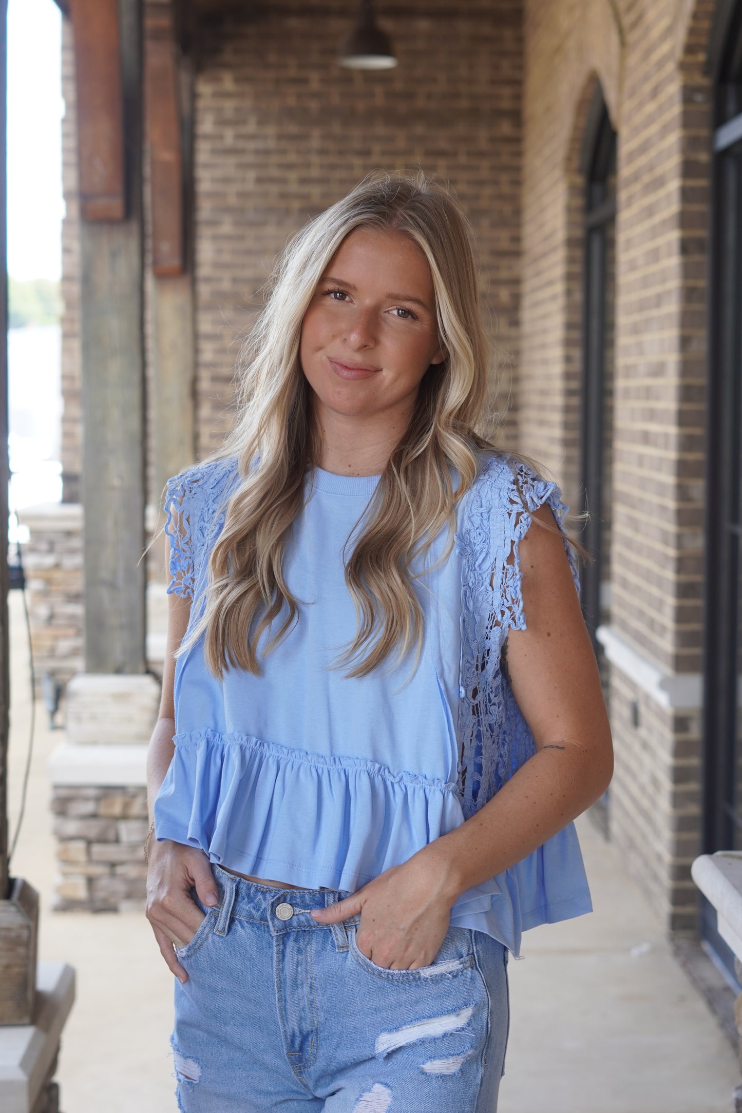 Blue sleeveless top. Ruffled bottom hem. From shoulder to beneath the armpit, lace trim, completely see-through. Semi-cropped. 