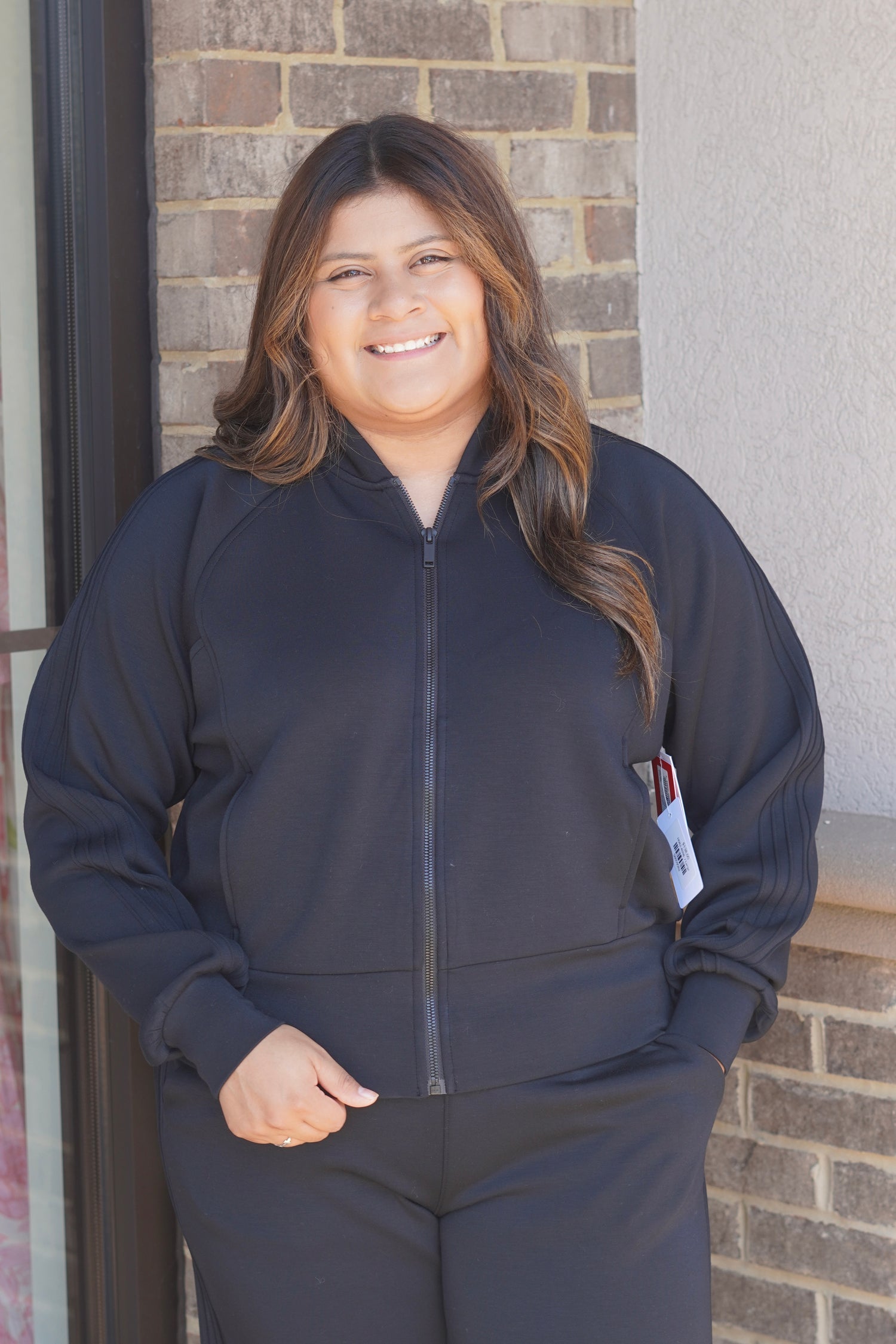 A woman wearing a black zip-up athletic jacket and matching black pants.