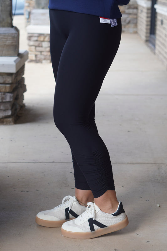 A person wearing black leggings, that a have a ruched on the side.