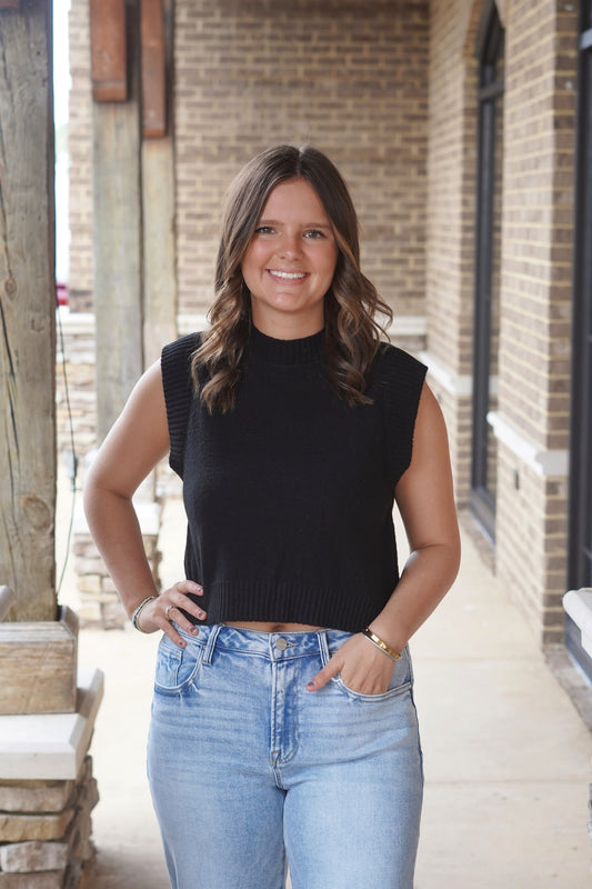 Woman wearing a black cropped relaxed fit sleeveless top paired with jeans 
