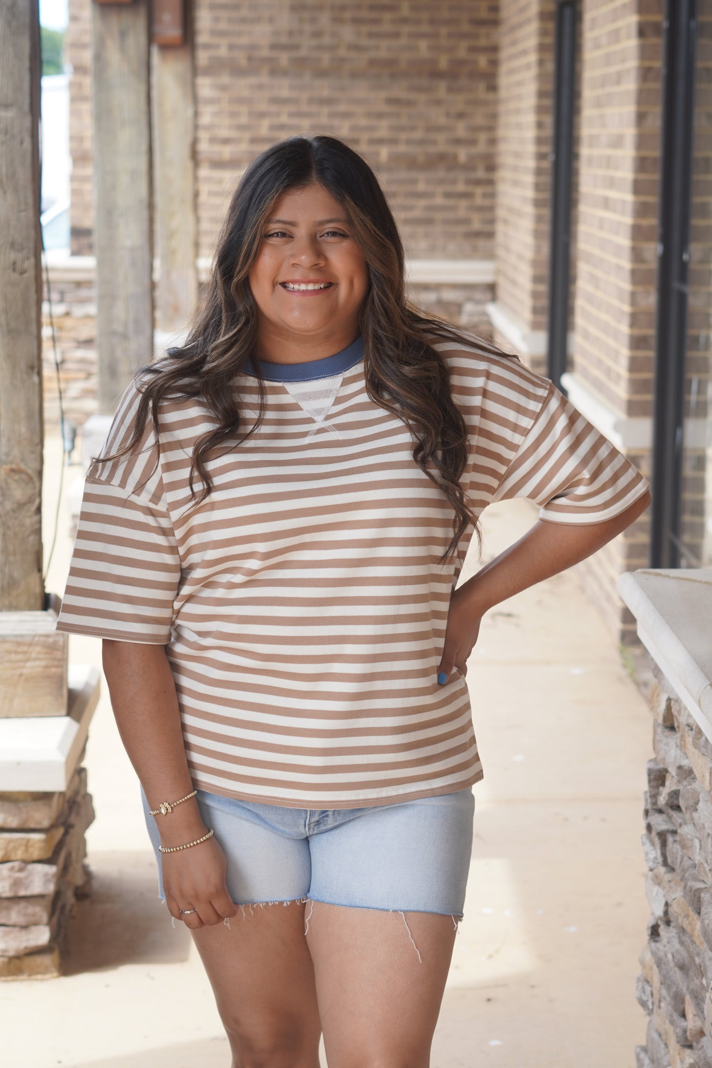 Women wearing a mocha striped top with a blue neckline 