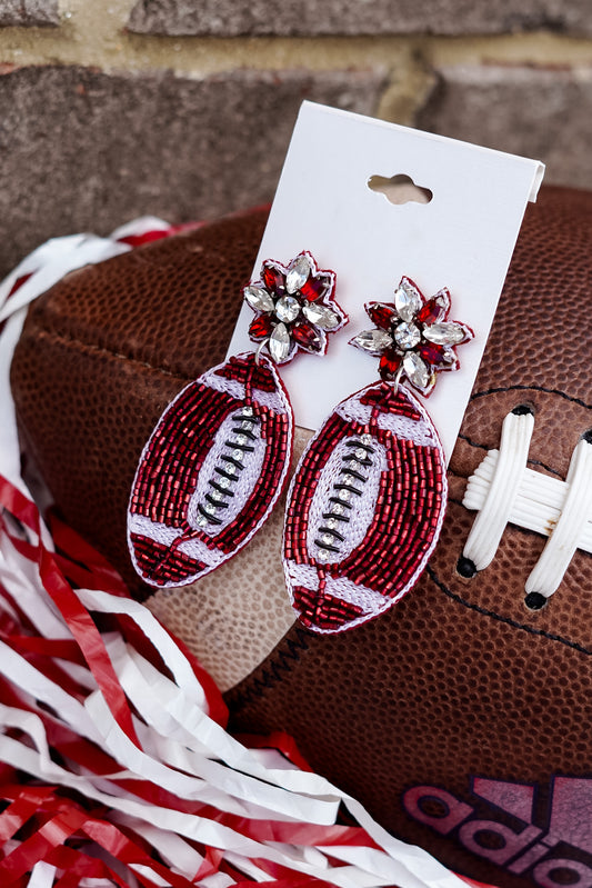 You want to dress up for the game this weekend, but still show your team pride!! These Crimson Embellished Football Earrings will pair perfectly with your outfit and show everyone who you are rooting for!!  Crimson Embellished Football Earrings Stud Post Back. Red beaded football outlined in white. 