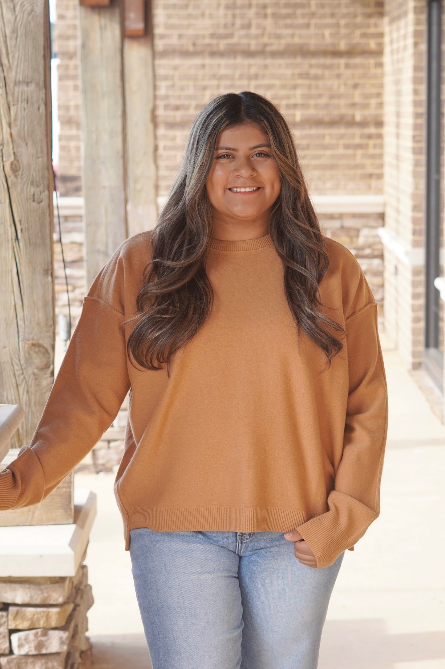 Woman wearing a mustard colored long sleeve sweater paired with light wash denim jeans 