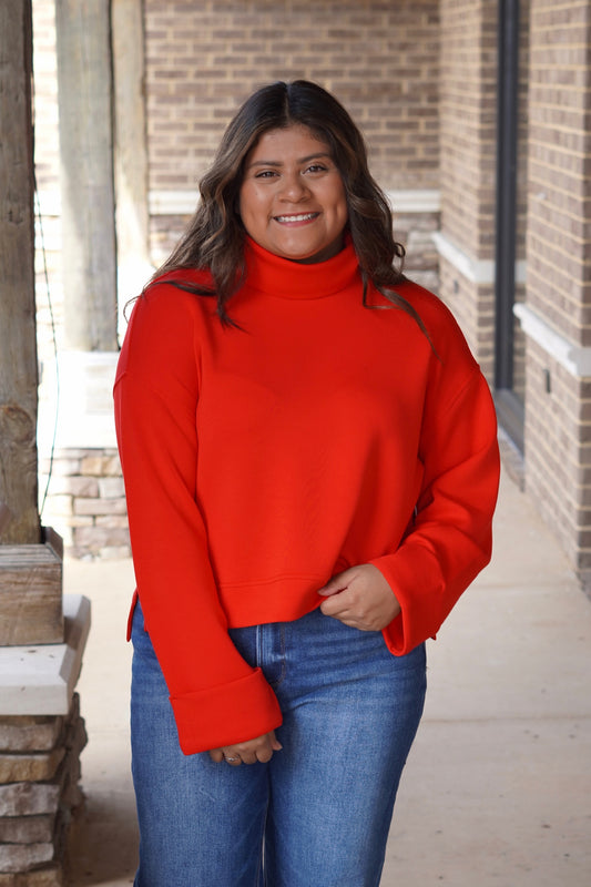 Women wearing a red turtleneck long sleeve top paired with jeans 