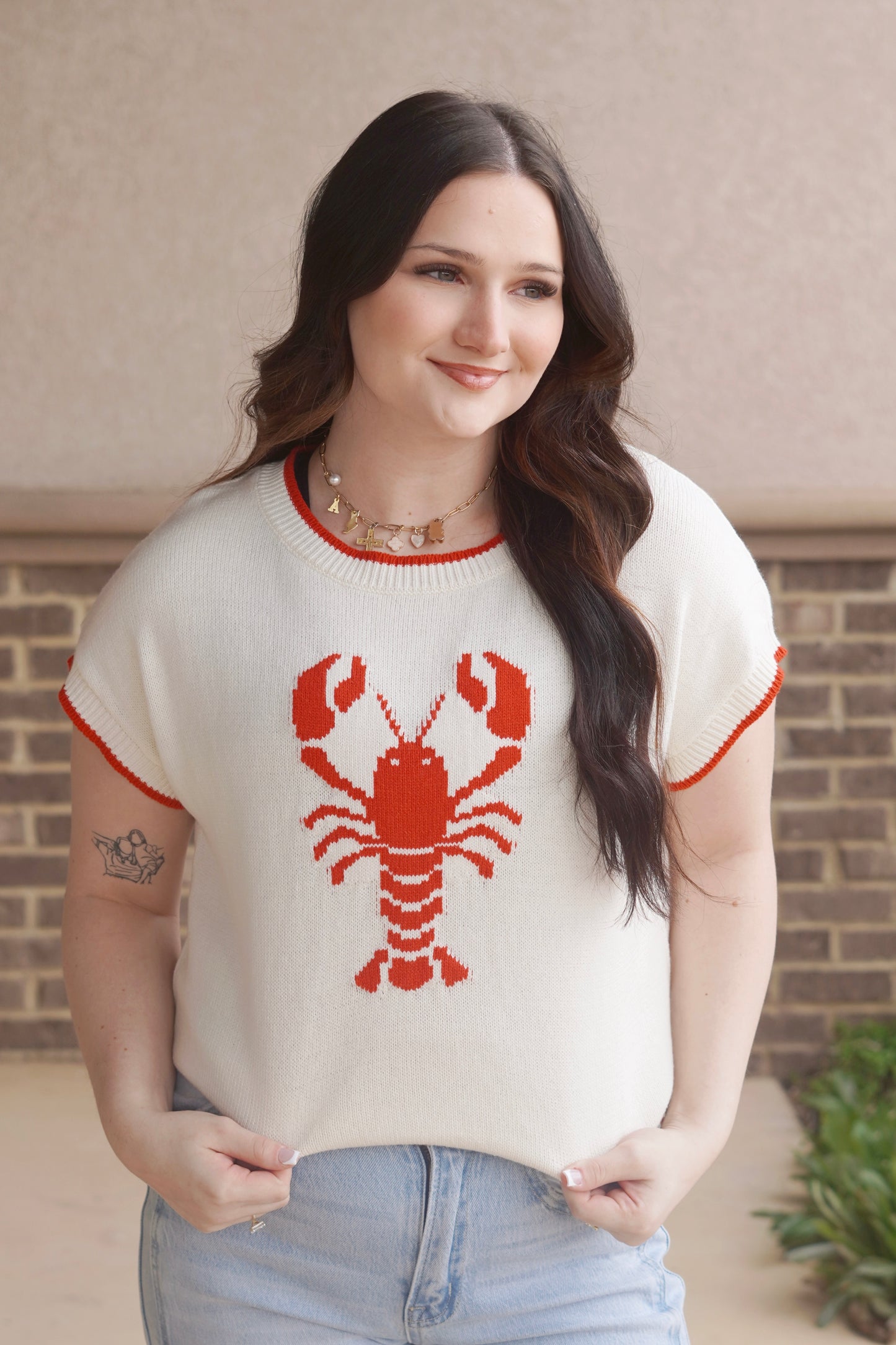 women wearing a white knit top with a red lobster in the center and red trim, round neckline, short sleeve.