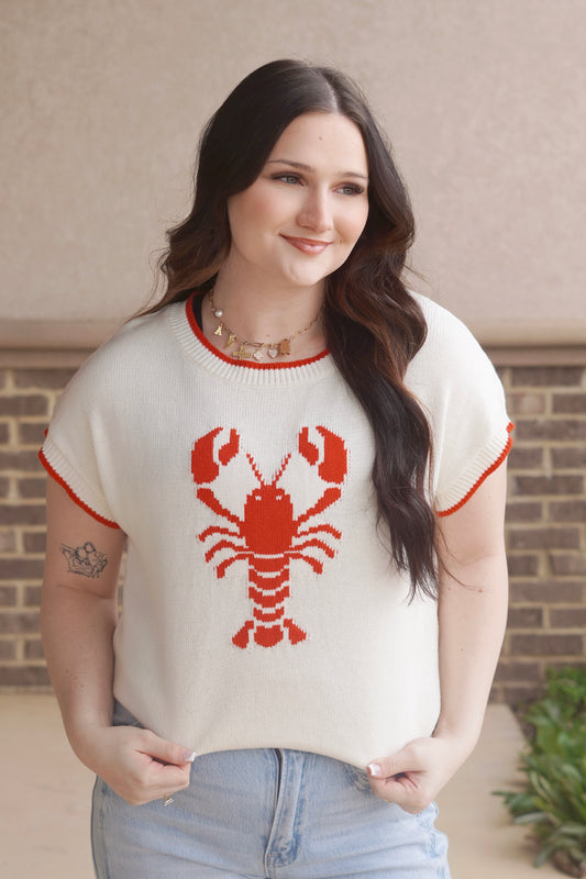 women wearing a white knit top with a red lobster in the center and red trim, round neckline, short sleeve.