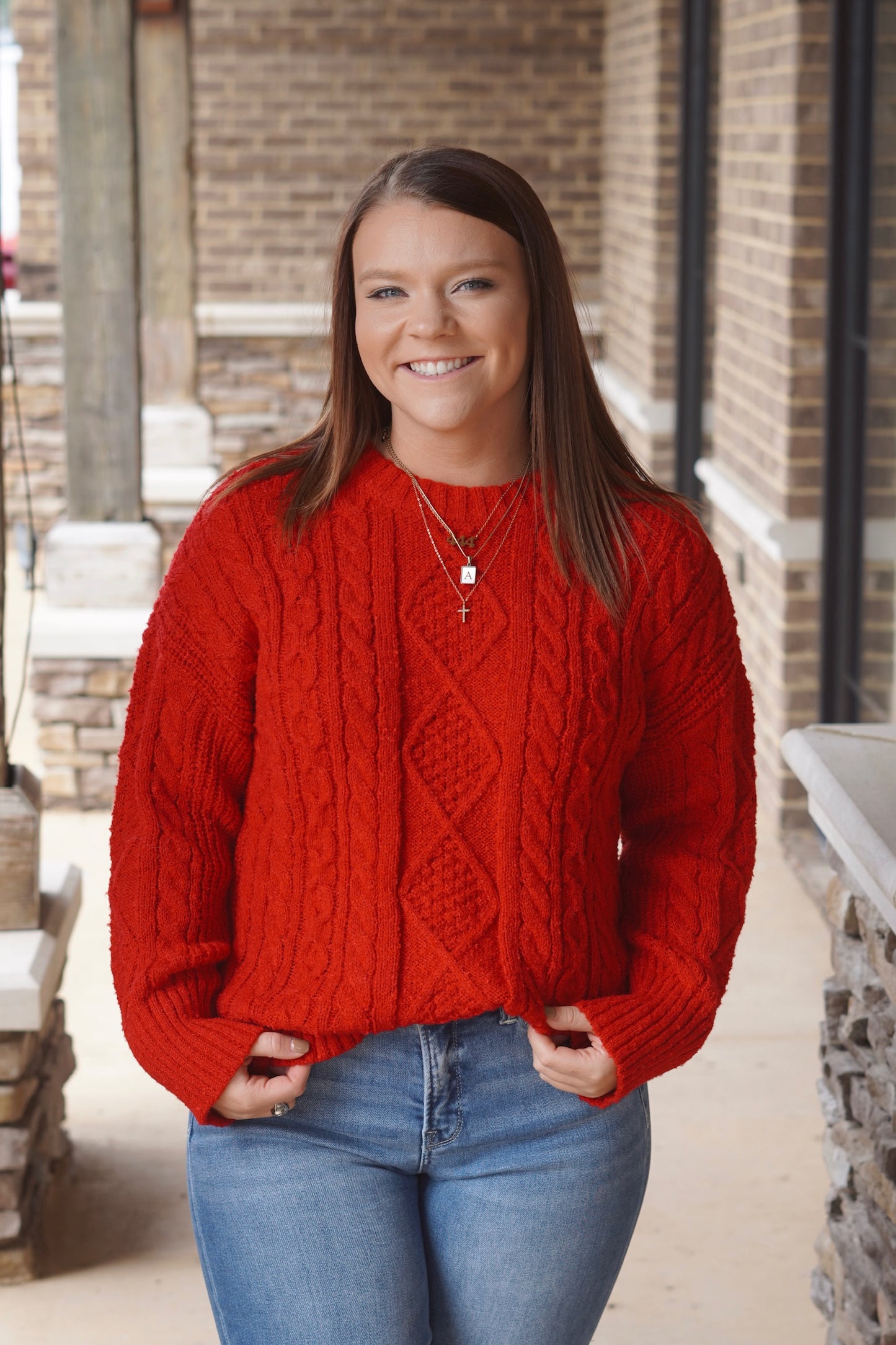 Woman wearing a Red Cable Knit long sleeve Sweater paired with blue jeans