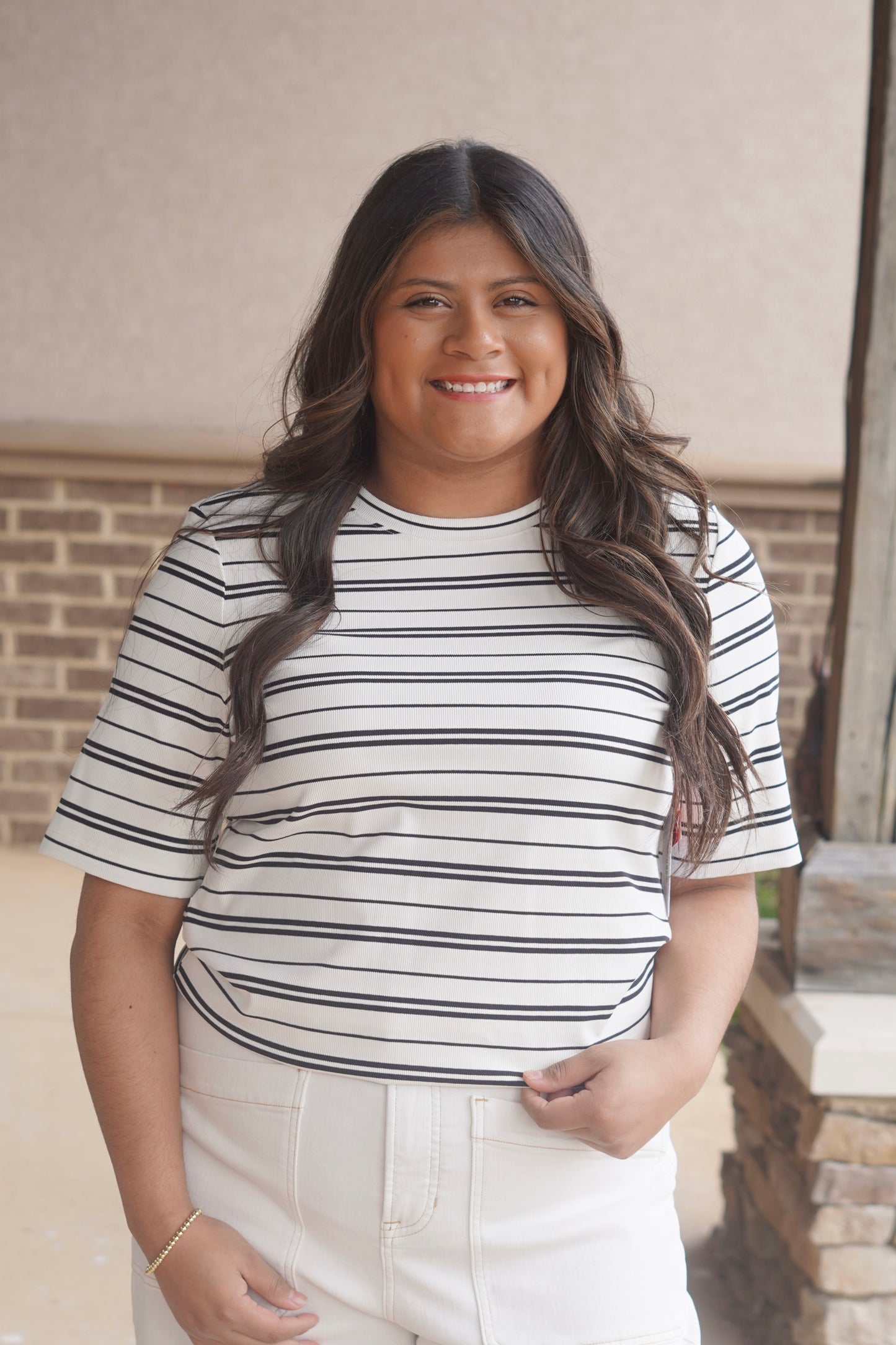 Women wearing a white with black short sleeve t shirt, round neckline, ribbed material. 