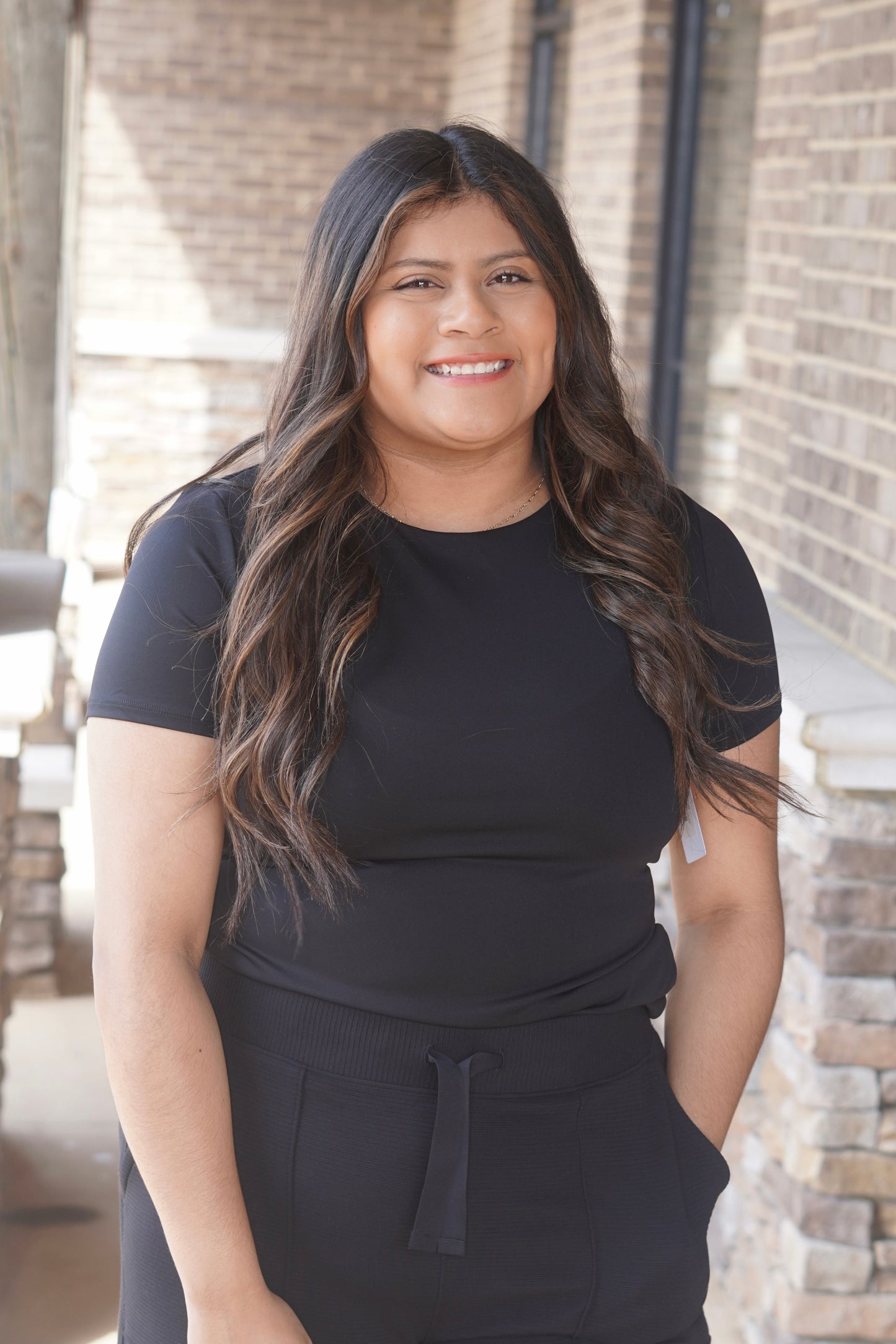 Women wearing a Black fitted short sleeve top, round neckline paired with black pants. 