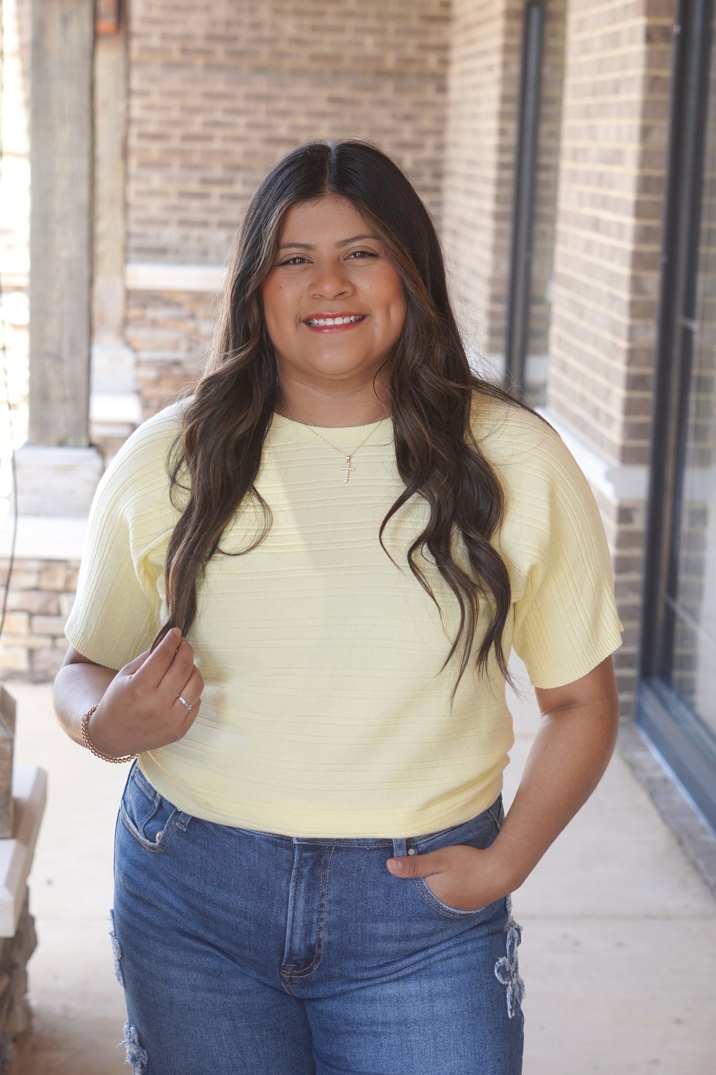 Woman wearing a yellow top, mid-length sleeves, round neckline and blue jeans