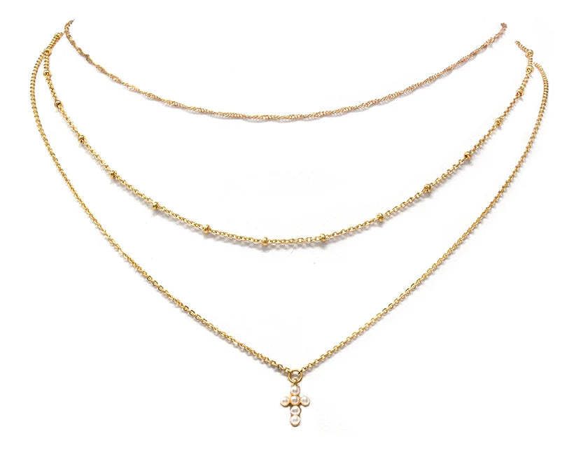 gold three layered necklace, a small beaded chain, a small pearl cross pendent in one of the necklaces. 