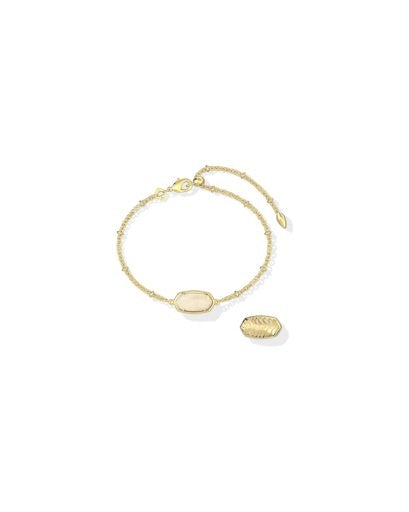 A delicate gold chain bracelet featuring a central oval cream-colored stone and a small textured gold leaf charm, displayed on a clean white background.