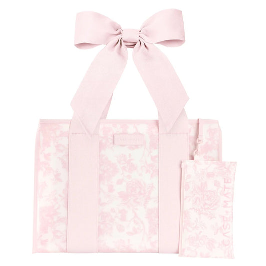 A light pink tote bag with a matching fabric bow on the handle and a small matching pouch, both featuring a subtle floral toile pattern on a white background.