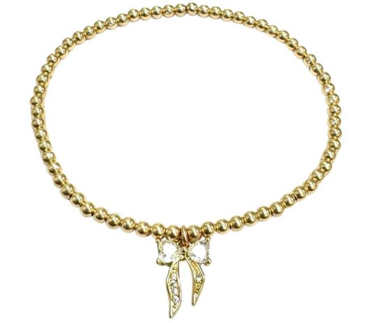 gold beaded bracelet with bow charm BALL BEAD MATERIALS: 14K GOLD FILLED, STERLING SILVER OR ROSE GOLD PENDANT MATERIAL: 18KG PLATED ON STERLING SILVER (GOLD ONLY) STONES: CUBIC ZIRCONIA STRETCHY LENGTH: 6.5" OR 7