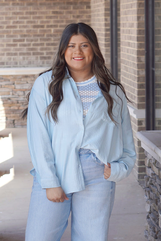 Women wearing a blue button up long sleeve, collar neckline styles with a top underneath and some light wash jeans.