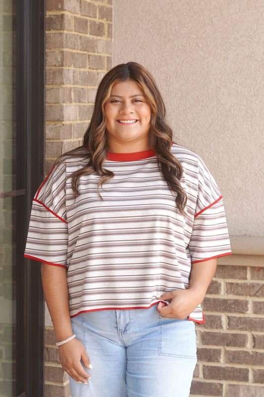 Women wearing short sleeve brown and white striped top, with a red trim. 