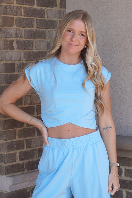 Women wearing a baby blue Crossover Top, Round Neckline, Cap Sleeves, slightly Cropped.