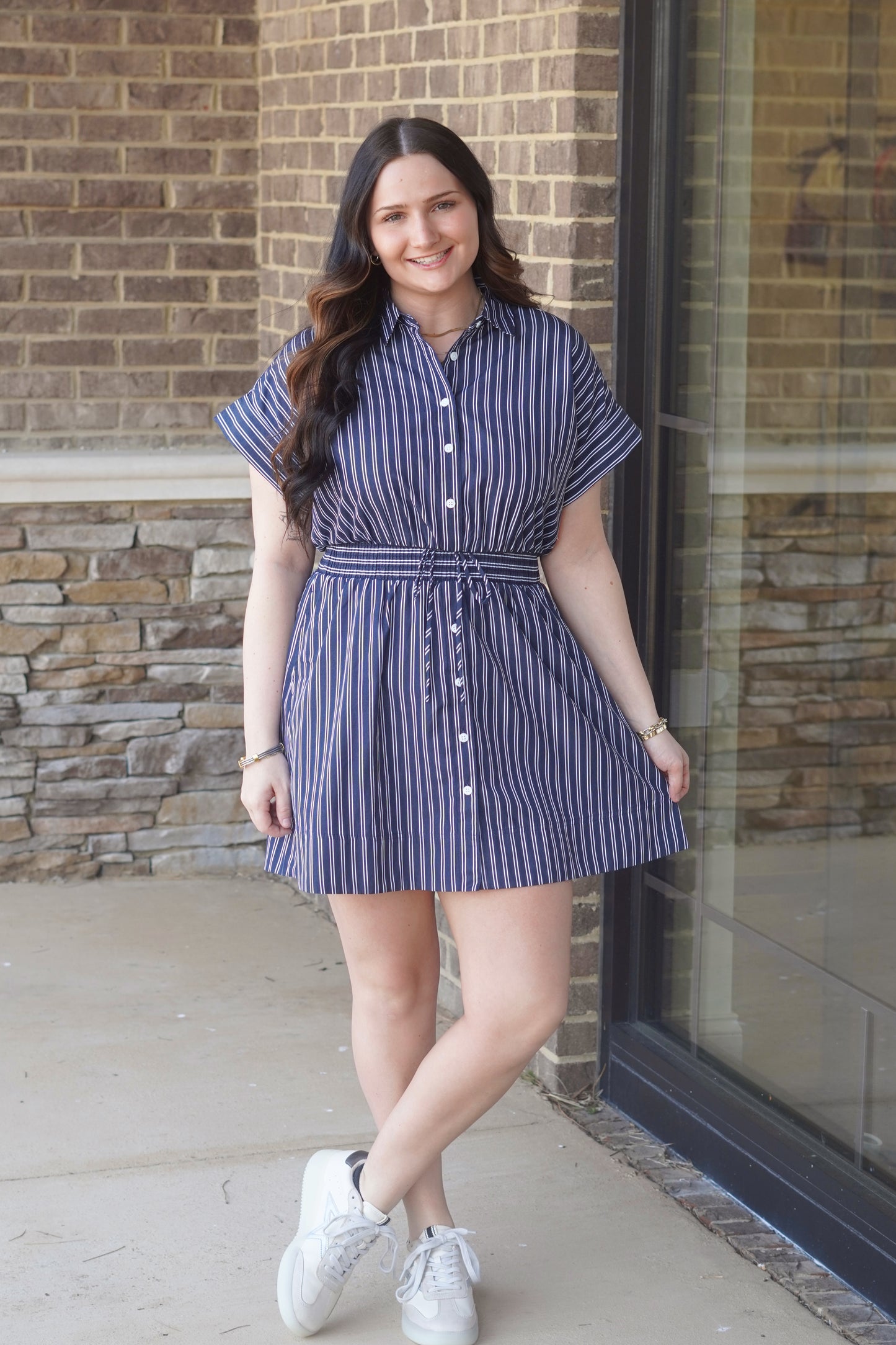Women wearing a navy and white stripes  short dress, button up style, elastic waistband, with shorts sleeves. 