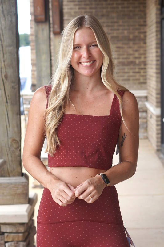 A woman wearing a matching burgundy crop top, square neckline with a tiny pink polka dot pattern.