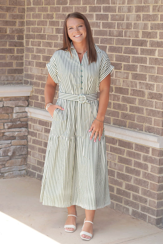 A woman wearing a green and white striped midi dress with a tie waist belt.