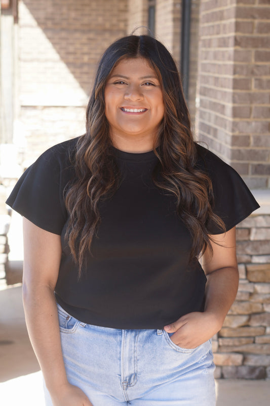 Women wearing a black top with flutter sleeves, and a round neckline. 