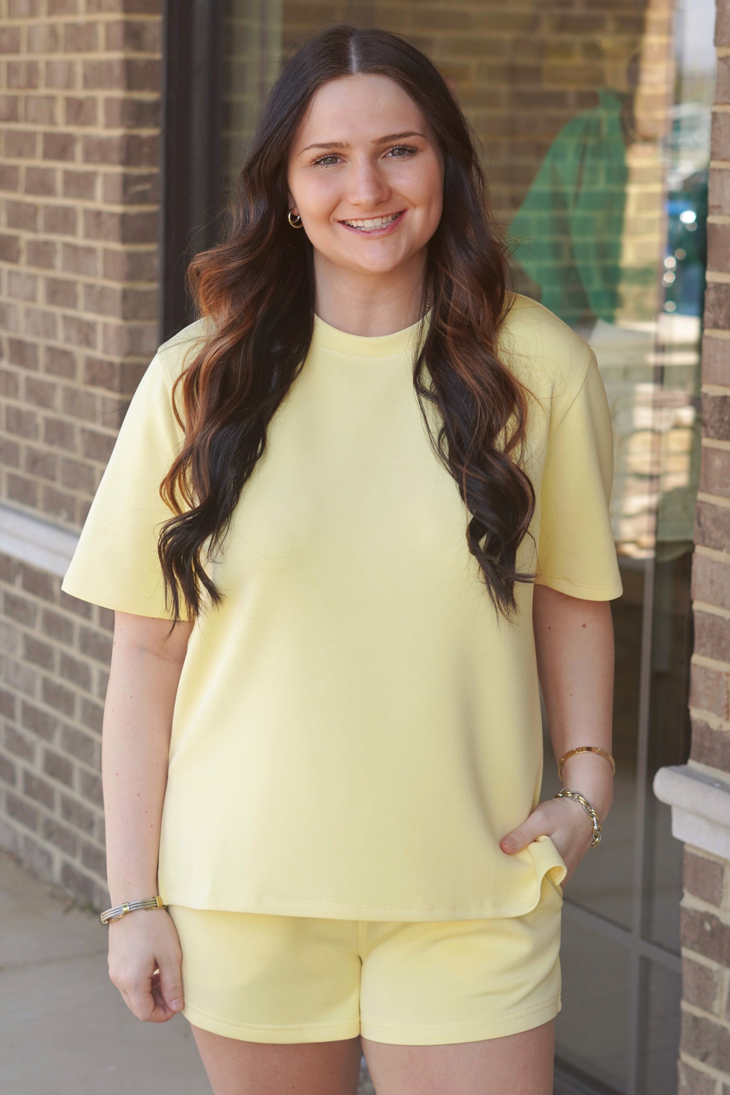 Woman wearing a yellow oversized short-sleeve tee with side slits, crew neckline, paired with matching yellow shorts. 