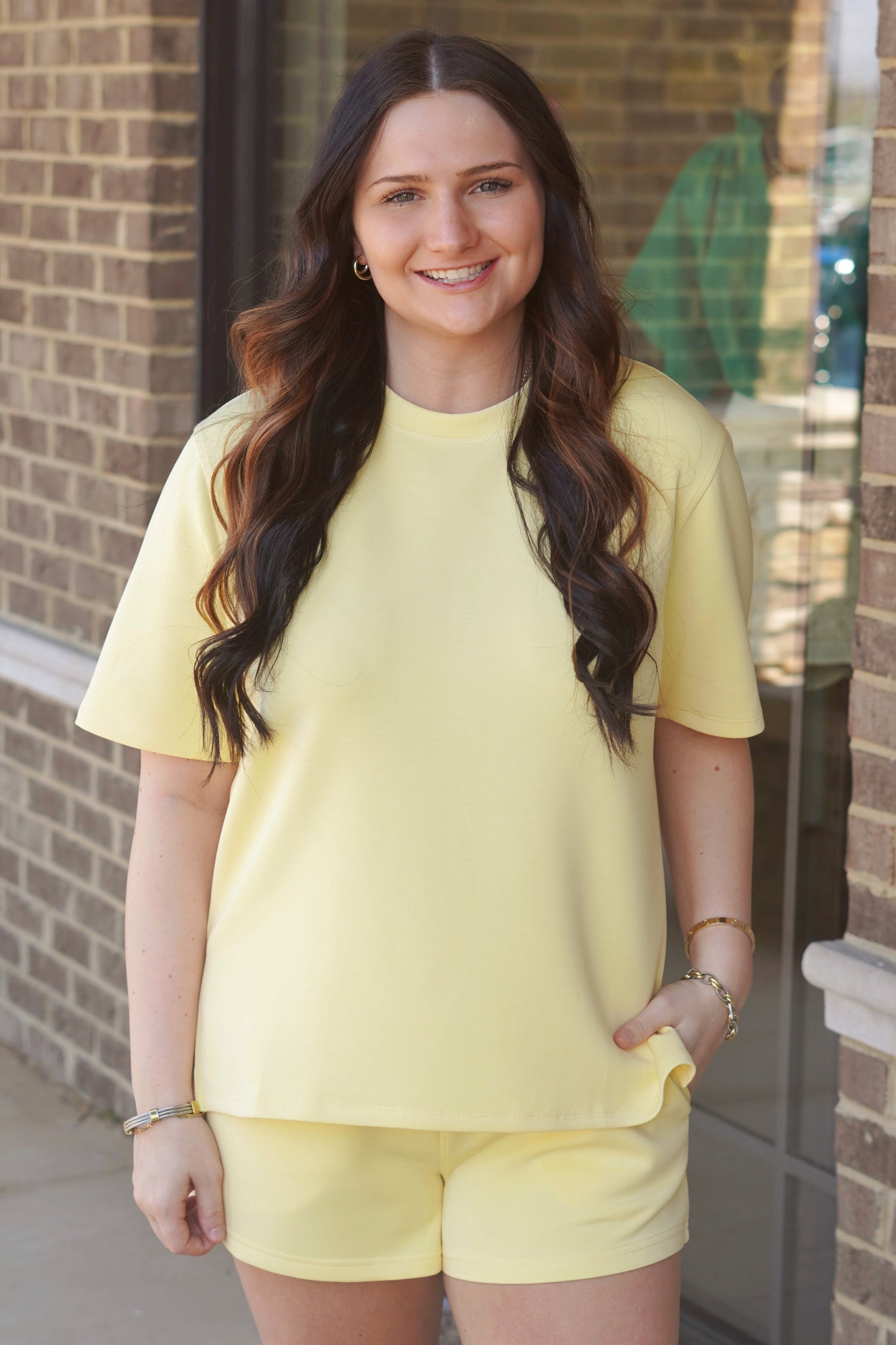 Woman wearing a yellow oversized short-sleeve tee with side slits, crew neckline, paired with matching yellow shorts. 
