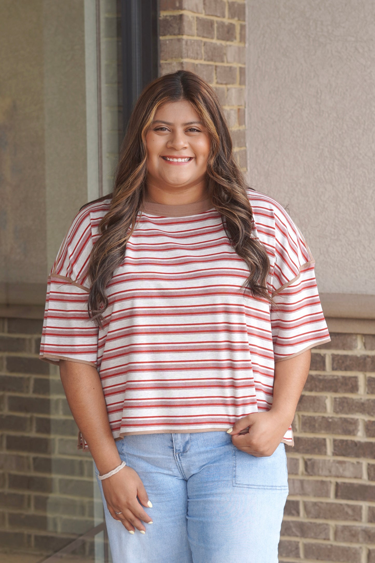 Women wearing short sleeve red and white striped top, with a brown trim. 